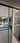 Modern double hinged glass door with black frame opening to bright tiled room and garden view