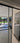 Modern double hinged glass door with black frame opening to bright tiled room and garden view