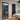 Interior view of black framed ribbed glass door beside tall black radiator and wooden dining chairs