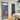 Interior dining area with ribbed glass hinged door in black frame, vertical dark radiator, wooden chairs