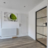 Modern interior with white hinged door, black-framed glass door, wood floor, and lime splash wall art