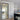 Modern hinged glass door with black metal frame between kitchen and dining area featuring chevron wood flooring