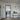 Modern interior with black framed hinged glass door leading to kitchen, white walls, console table with vases and flowers