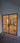 Double hinged black metal frame glass doors leading to a construction area with ladder and wooden planks