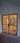 Double hinged black metal frame glass doors leading to a construction area with ladder and wooden planks