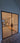 Modern black steel frame double hinged glass door in an unfinished room with wooden boards and stairs inside