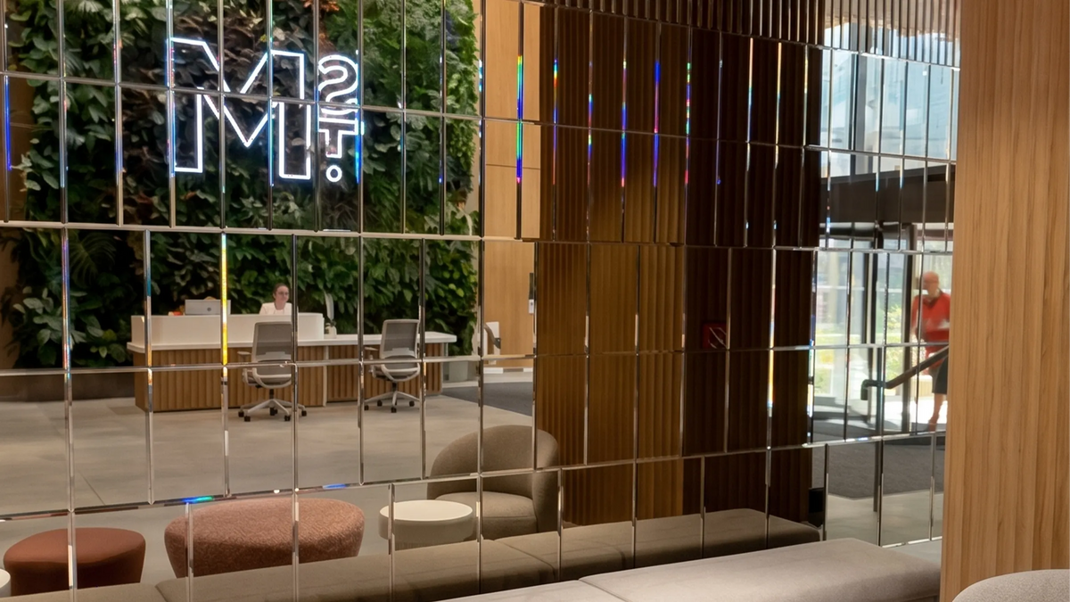 Bespoke mirrored glass wall with LED neon sign in modern office lobby, featuring feature mirrors and decorative glass panels