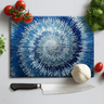 Blue spiral printed chopping board with chef knife, garlic, basil, cherry tomatoes on white surface