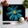 Cerulean daisy design on black chopping board with kitchen knife, tomatoes, garlic, and herbs