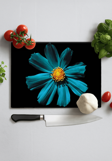 Cerulean daisy design on black chopping board with kitchen knife, tomatoes, garlic, and herbs