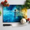 Colorful astronaut design glass chopping board with tomatoes, basil, garlic, and knife on white surface