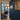 Modern interior with hinged black metal frame glass door, blue wall with photo collage, and wooden floor
