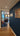 Modern interior with hinged black metal frame glass door, blue wall with photo collage, and wooden floor