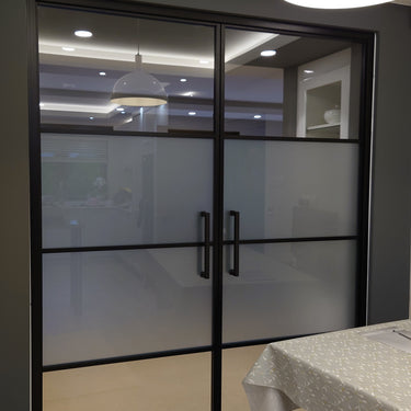 Double hinged black framed glass doors with frosted middle panels in modern interior