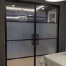 Double hinged black framed glass doors with frosted middle panels in modern interior