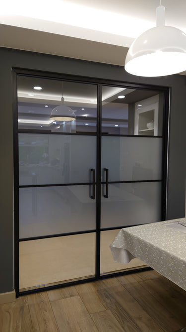 Double hinged black framed glass doors with frosted middle panels in modern interior