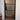 Black framed glass hinged door with horizontal bars in a bright interior hallway