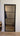Black framed glass hinged door with horizontal bars in a bright interior hallway