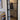 Modern black metal framed hinged glass door in bright interior with wooden floor and couch