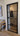 Modern black metal framed hinged glass door in bright interior with wooden floor and couch