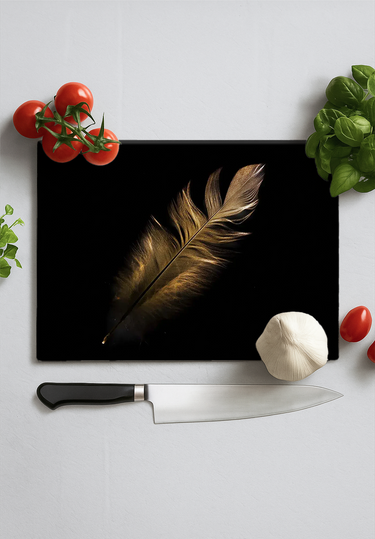 Black chopping board with golden feather print surrounded by cherry tomatoes, garlic, basil, and kitchen knife