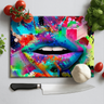 Colorful graffiti-style lips on a chopping board with knife, tomatoes, garlic, and herbs nearby