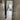 View through black-framed glass door into modern kitchen with light wood floor and stairs