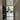 Black metal frame glass door opening to a modern kitchen with light wood floors and shoe rack