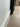 Close-up of light wood floor with white baseboard and black metal furniture frame near a wall, cardboard boxes in background