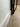 Close-up of a black metal door frame near a white wall with light wood flooring and cardboard box in background