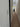 Narrow hallway with wooden floor, white walls, coat on rack, and front door in background