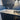 Modern kitchen countertop with white marble pattern, blue glossy backsplash, and stainless steel gas stove