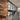Modern interior hallway with black metal framed glass partition, exposed brick wall, and wooden floor under renovation