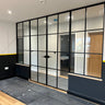 Modern black metal framed double doors with glass panels and two side panels in a contemporary room