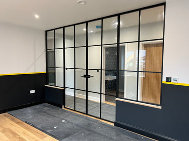 Modern black metal framed double doors with glass panels and two side panels in a contemporary room