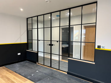 Modern black metal framed double doors with glass panels and two side panels in a contemporary room