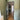 Modern black framed glass door in green-painted room opening to hallway with wood herringbone floor