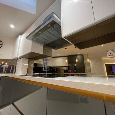 Modern kitchen with sleek glass splashback and reflective surfaces, featuring bespoke architectural glass design.