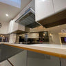 Modern kitchen with sleek glass splashback and reflective surfaces, featuring bespoke architectural glass design.