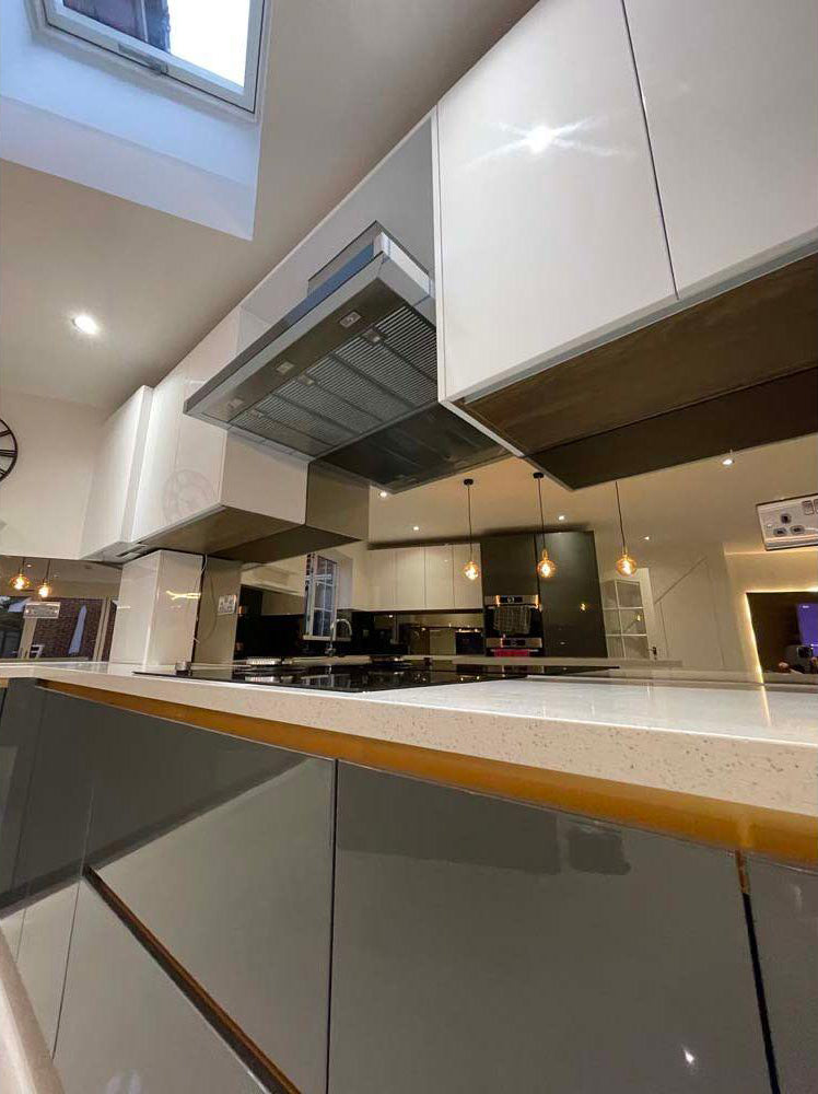 Modern kitchen with sleek glass splashback and reflective surfaces, featuring bespoke architectural glass design.