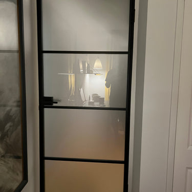 Black metal framed frosted glass interior door with home office seen through glass
