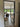 Open black-framed glass door leading to living room with brown armchair and dog by large sliding garden doors