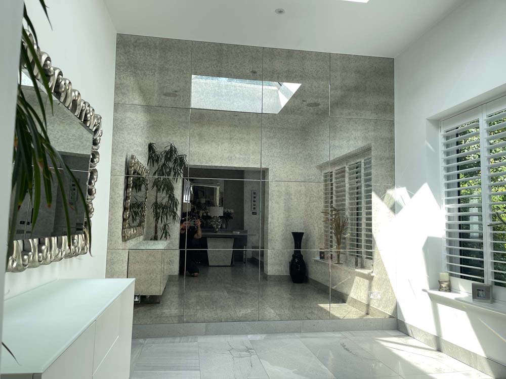 Bespoke architectural glass mirror wall in modern luxury interior with skylight and decorative accents