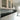 Modern kitchen with sleek white cabinets, black countertop, and grey glass splashback