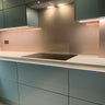 modern kitchen with sleek light blue cabinets, white quartz countertop, and glass backsplash with built-in stove