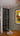 Modern interior with black framed glass hinged door, wooden floor, wooden table, and colorful framed artwork