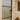 Modern frosted glass hinged door with black frame in a white interior hallway featuring stained glass and wooden decorative vase stand
