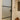 Modern frosted glass hinged door with black frame in a white interior hallway featuring stained glass and wooden decorative vase stand