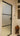 Modern frosted glass hinged door with black frame in a white interior hallway featuring stained glass and wooden decorative vase stand