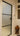 Modern frosted glass hinged door with black frame in a white interior hallway featuring stained glass and wooden decorative vase stand